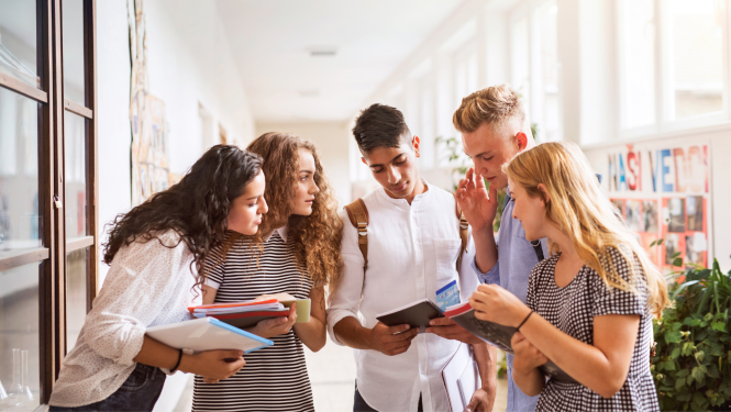dažādu nacionalitāšu studneti stāv augstskolas koridorā un kopā skatās kladē