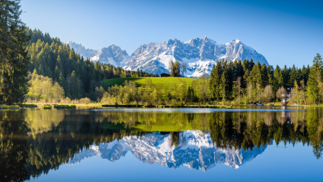 Austrijas dabas skats ar apsnigušiem kalniem uz ezeru priekšplānā