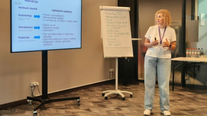 VIAA pārstāve stāv pie tāfeles seminārā pedagogiem 