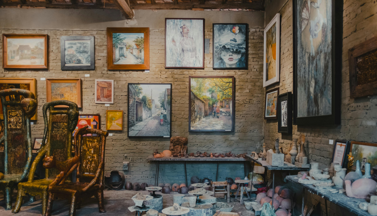 attēlā makslas galerija ar gleznām pie sienas un māla traukiem uz grīdas