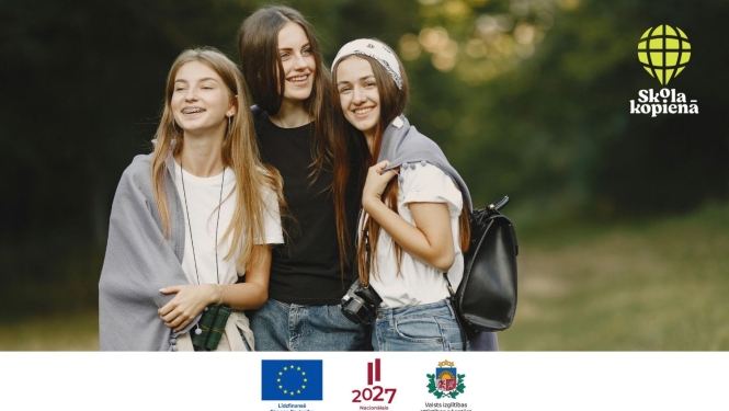 attēlā trīs jaunas meitenes stāv kopā un smaida, fonā zaļi koki, zāle; stūrī Skola-kopienā logo