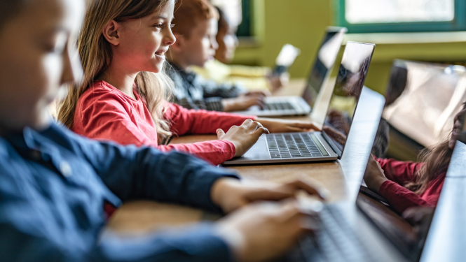 skolēni sēž pie datoriem datorklasē