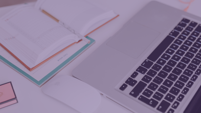 portatīvais dators atvērts uz galda un blakus atvērta pierakstu klade