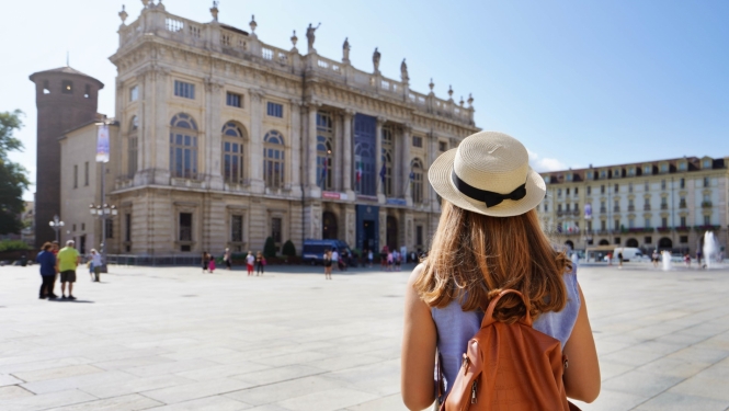 skats uz Itālijas arhitektūru Itālijas pilsētā priekšplānā ar muguru stāv jauna meitene ar mugursomu