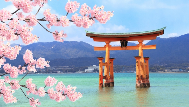skats uz Japānas kalniem ar ezeru priekšplānā ziedošās sakuras zariņi