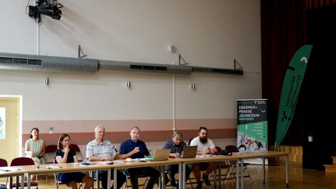 Cilvēku grupa sēž pie galva lielajā sporta hallē