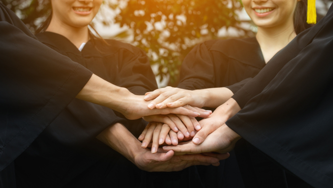 Rokas saliktas viena virs otras, fonā cilvēki