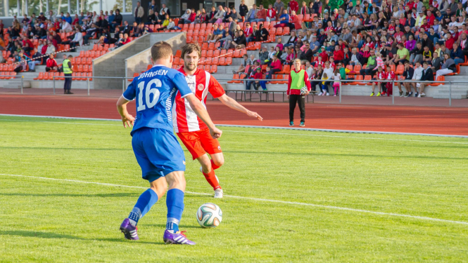 Divi vīrieši spēlē futbolu stadionā