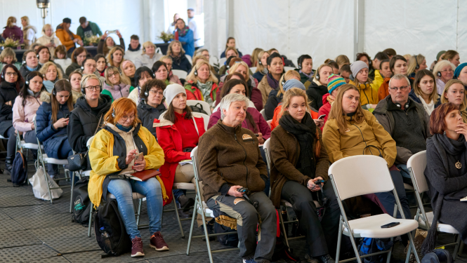 Cilvēki sēž un klausās semināru