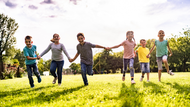 Bērni skrien pa saulainu pļavu