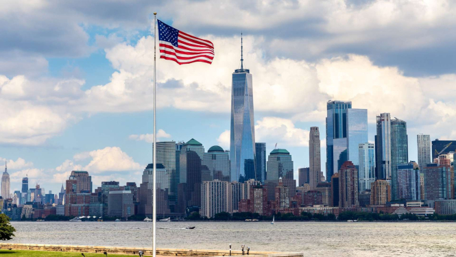 Amerikas karogs plīvo, aizmugurējā plānā pilsēta ar augstceltnēm