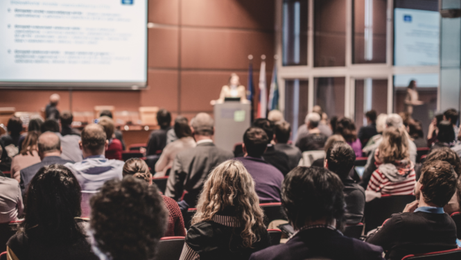 Cilvēku grupa sēž un klausās semināru