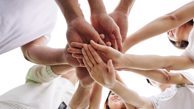 attēlā vairāki jauni cilvēki stāv aplī uz salika priekšā rokas kopā vienu otrai