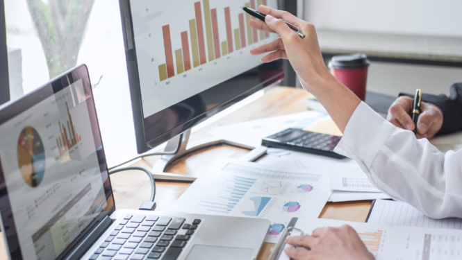 Sieviete strādā ar datoriem, tajos attēloti grafiki