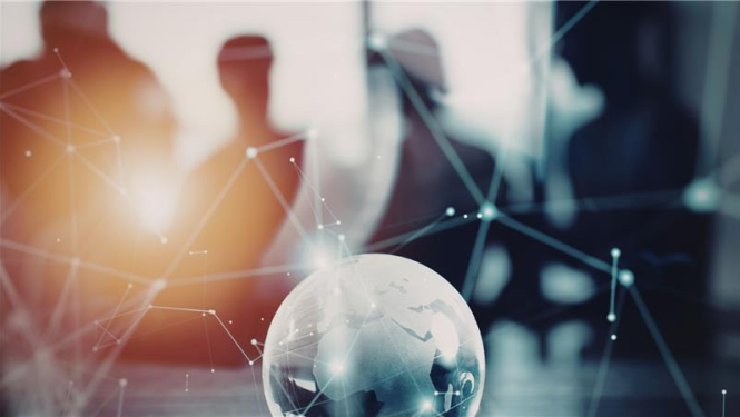 attēlā fonā stāv cilvēki biroja telpās (redzamas tikai ēnas) priekšplānā uz galda zemeslode stilizēta, uz bildes dekoratīvas tīkla līnijas