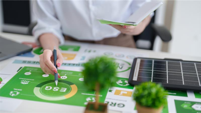 Erasmus seminārs par vidi, klimatu un zaļo pāreju, sieviete pie galda atzīmē ar pildspalvu zaļā zīmējumā