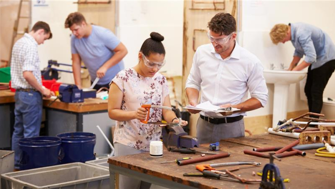 sieviete strādā ar zāģi vīrietis skatās kā viņa strādā, aizmugurē'jā plānā arī strādā trīs vīrieši ar žāģi