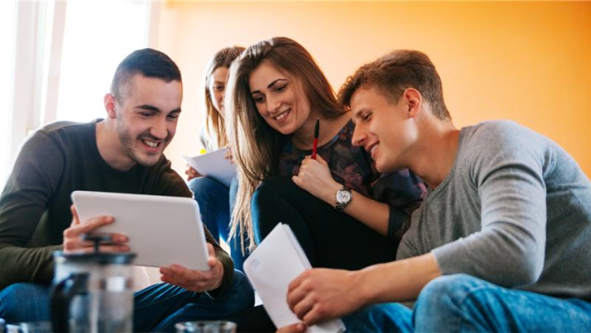 trīs studenti skatās kopā izdrukātas lapas un apspriež