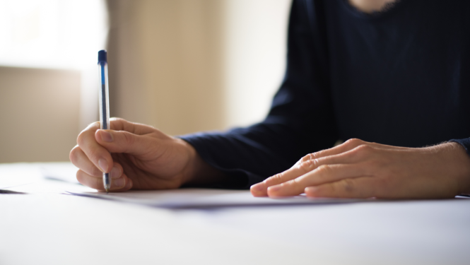 Cilvēks raksta ar pildspalvu