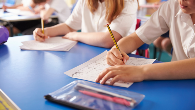 Skolēnu rokas ar zīmuļiem raksta uz papīra