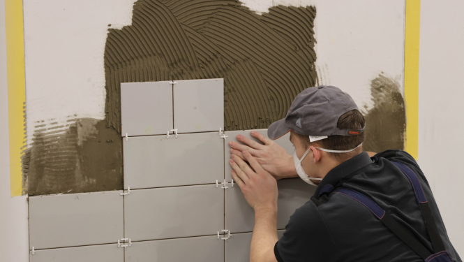 SkillsLatvia 2026 pusfināla flīzēšanas konkursa dalībnieks pila uzdevumu