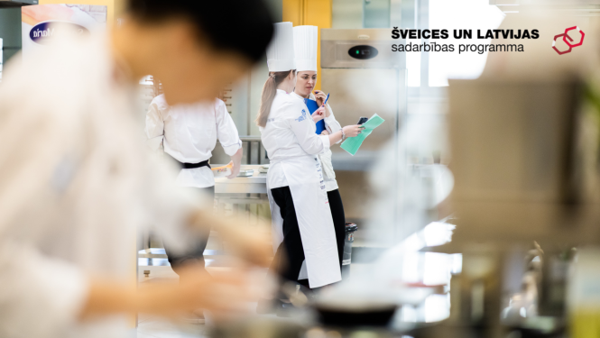 Māceklis pavārs priekšplānā gatavo aizmugurējā plānā pavāru pasniedzējs sniedz norādījumus