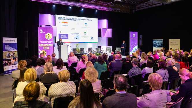 Cilvēki zālē klausās konference