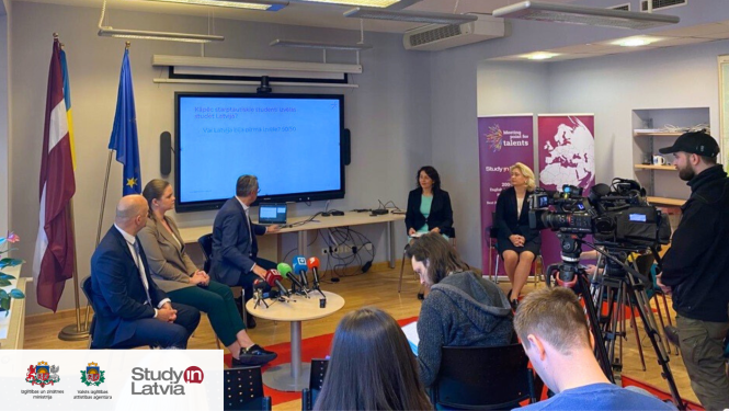 Cilvēki sēž pasākumā un prezentē