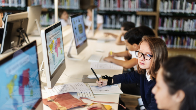 bērni sēž pie datoriem un mācās