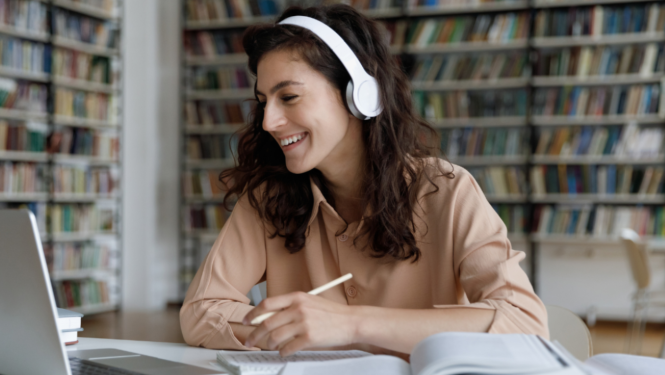 Sieviete ar austiņām skatās datorā un veic pierakstus