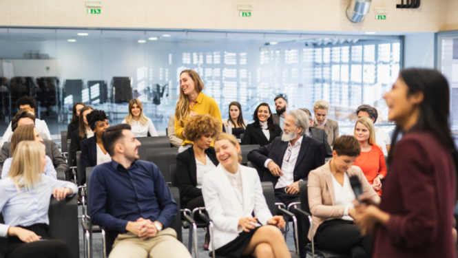 Cilvēku grupa sēž un klausās semināru