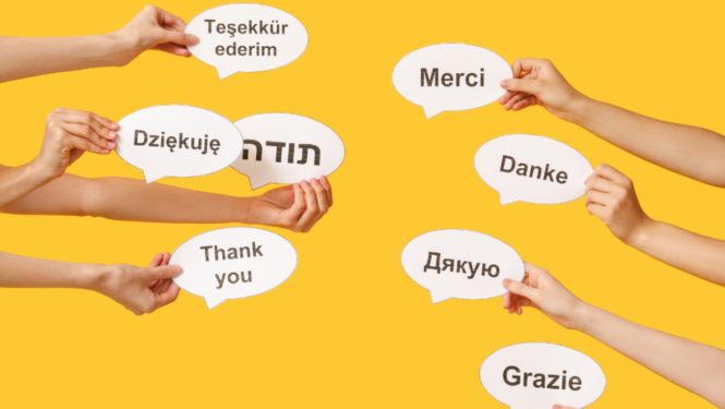 Rokas tura lapiņas uz kurām rakstīts vārds -  paldies, dažādās valodās