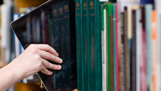 Digitālo planšeti ievieto plauktā starp grāmatām