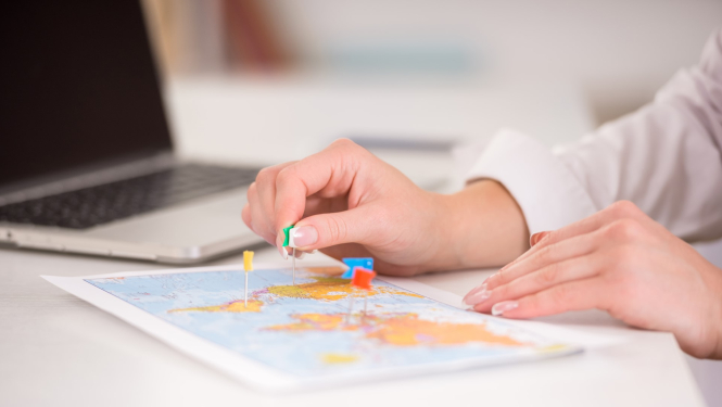 sieviete atzīmē vietas ar piespraužamām adatiņām kartē 