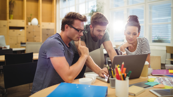 divi vīrieši un viena sieviete strādā kopā pie viena datora