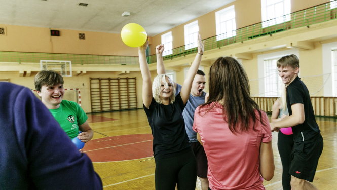 Priecīga meitene sporta zālē ar balonu rokās