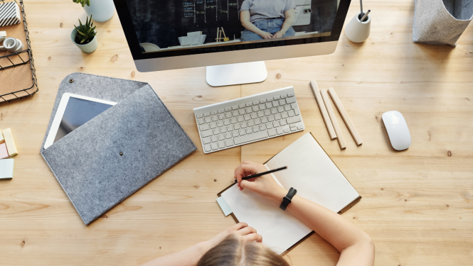 sieviete pie datora mācās un raksta burtnīcā