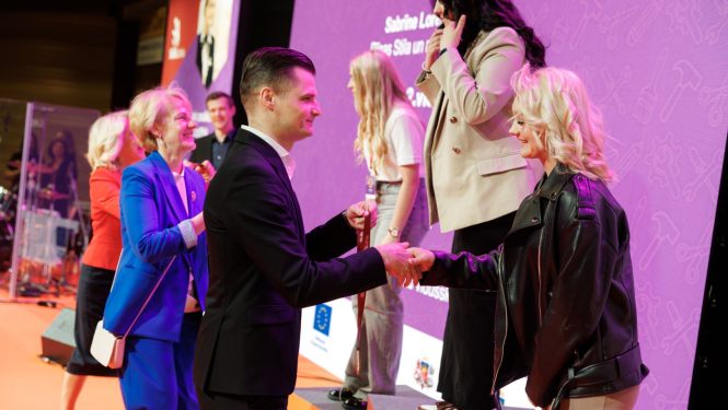 Cilvēki pasniedz medaļas jauniešiem uz pjedestāla