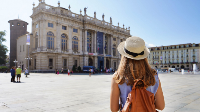 skats uz Itālijas arhitektūru Itālijas pilsētā priekšplānā ar muguru stāv jauna meitene ar mugursomu