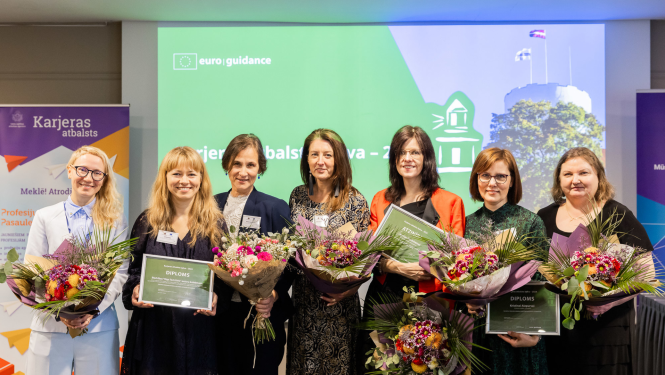 Sievietes stāv ar apbalvojumiem un ziediem