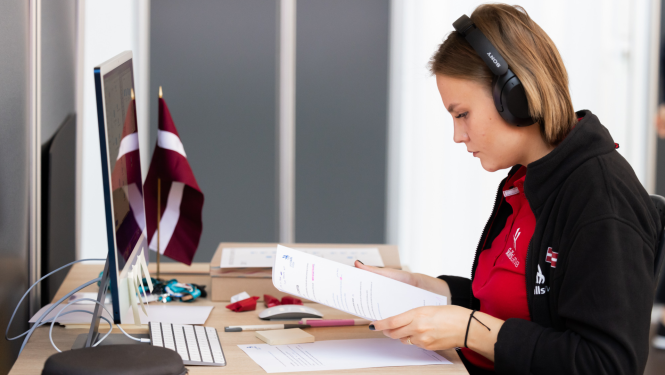 Jauniete pie datora ar austiņām lasa tekstu no lapas