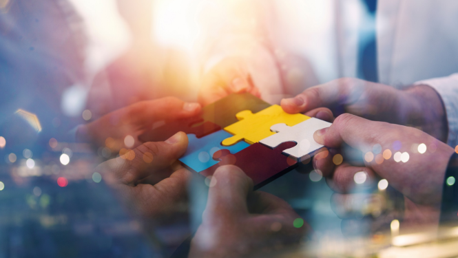 vairāki cilvēki rokās tur puzles gabaliņus un saliek tos kopā