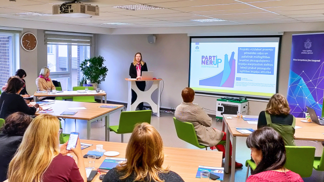 Cilvēki sēž un klausās semināru