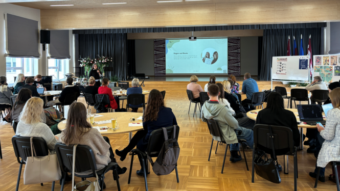 Cilvēki zālē sēž pie galdiem