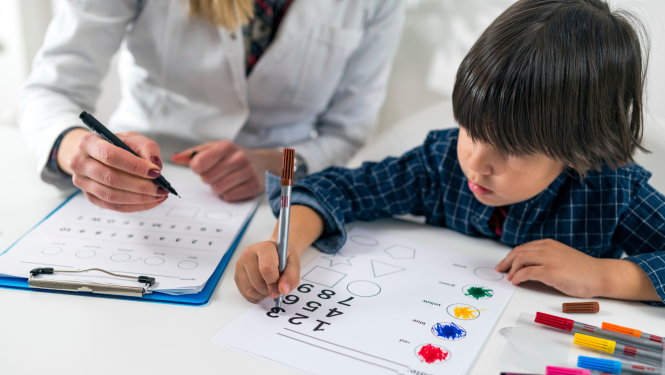 pedagogiski mediciniskais komisijas specialists diognistice skolenu, pieraksta datus uz lapas, skolens pilda uzdevumu