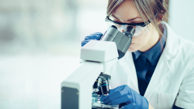 Sieviete strādā pie mikroskopa