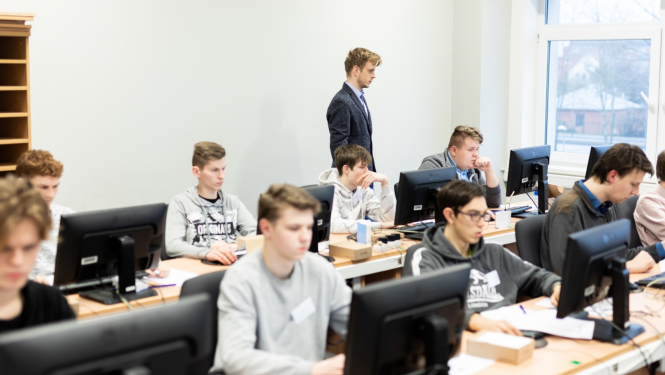 SkillsLatvia pusfinala "Datortiklu administresana" dalibnieki sez pie datoriem konkursa laika