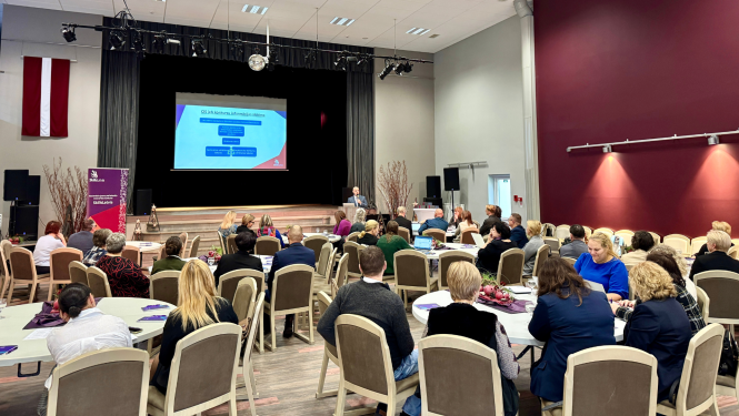 Cilvēki sēž aktu zālē pasākumā