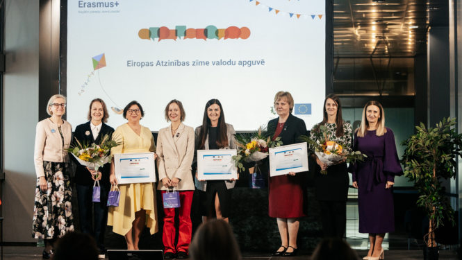 Sievietes stāv uz skatuves ar ziediem rokās