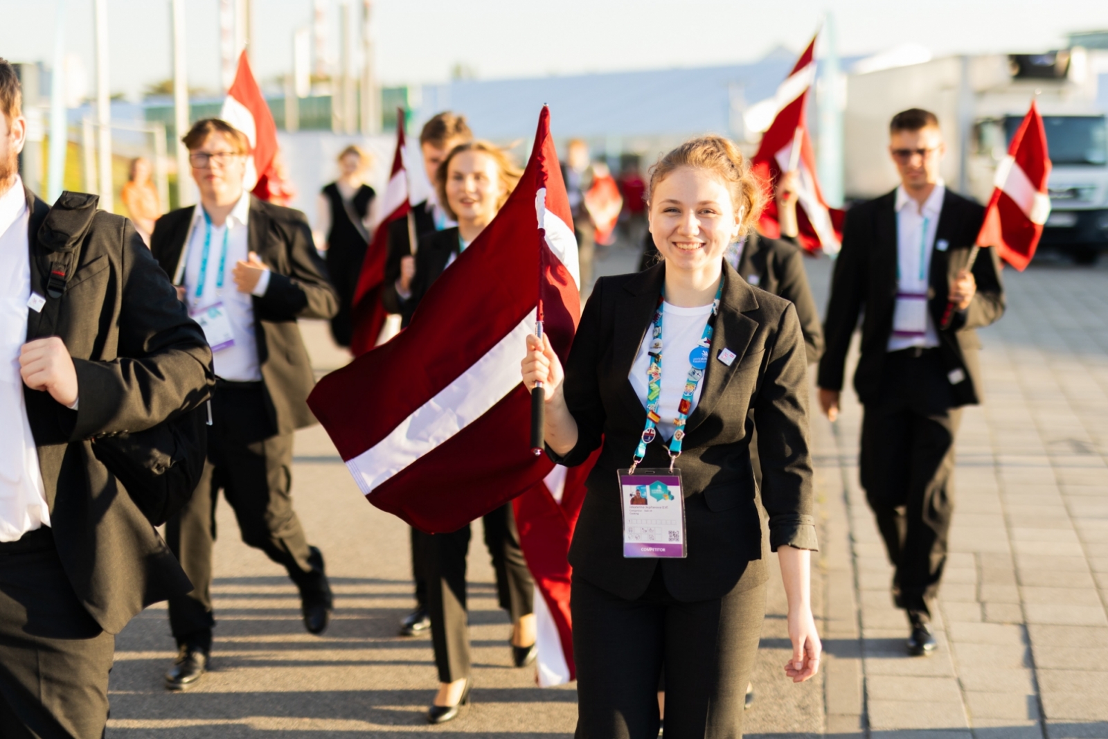 Jaunieši ar Latvijas karogiem iet parādē